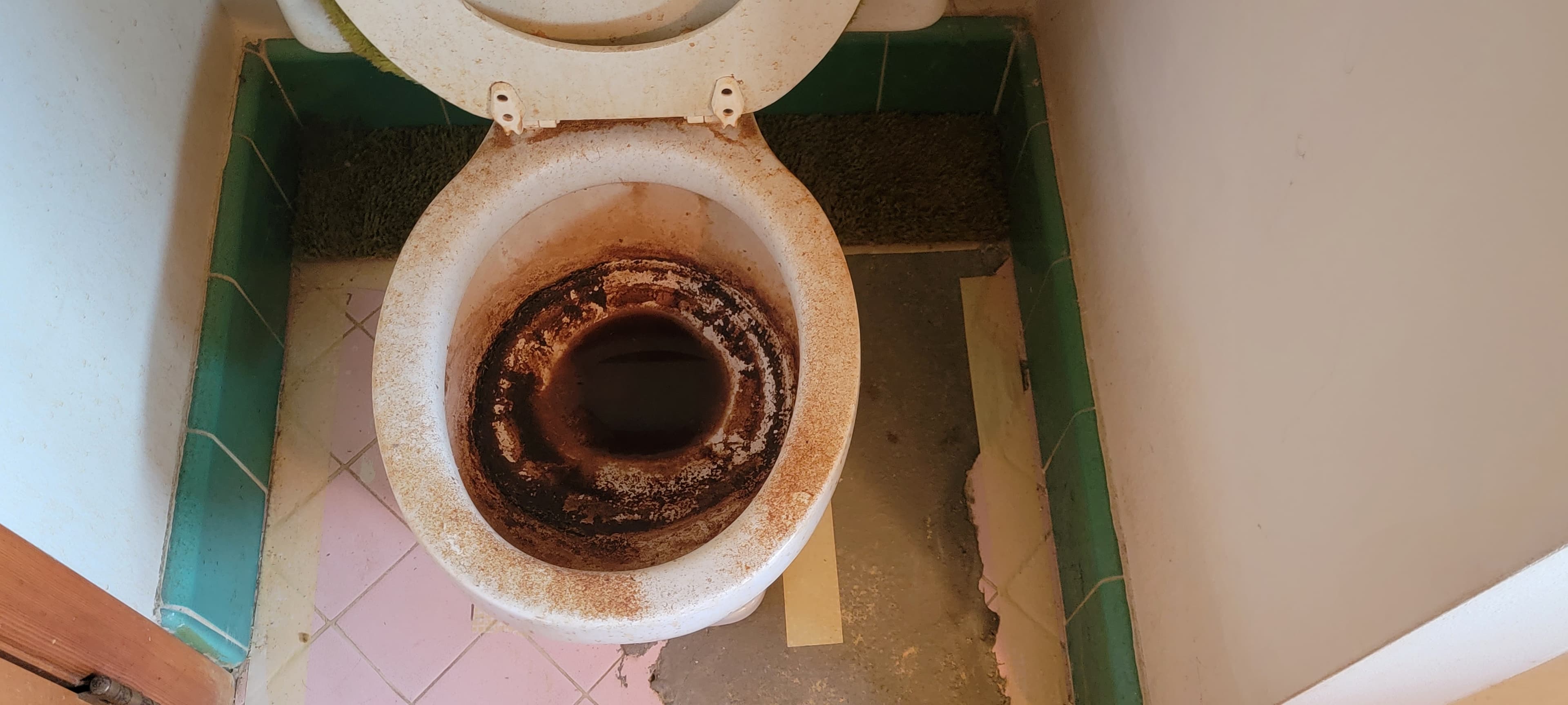 Toilet before deep cleaning, with decades of heavy mineral and soil buildup