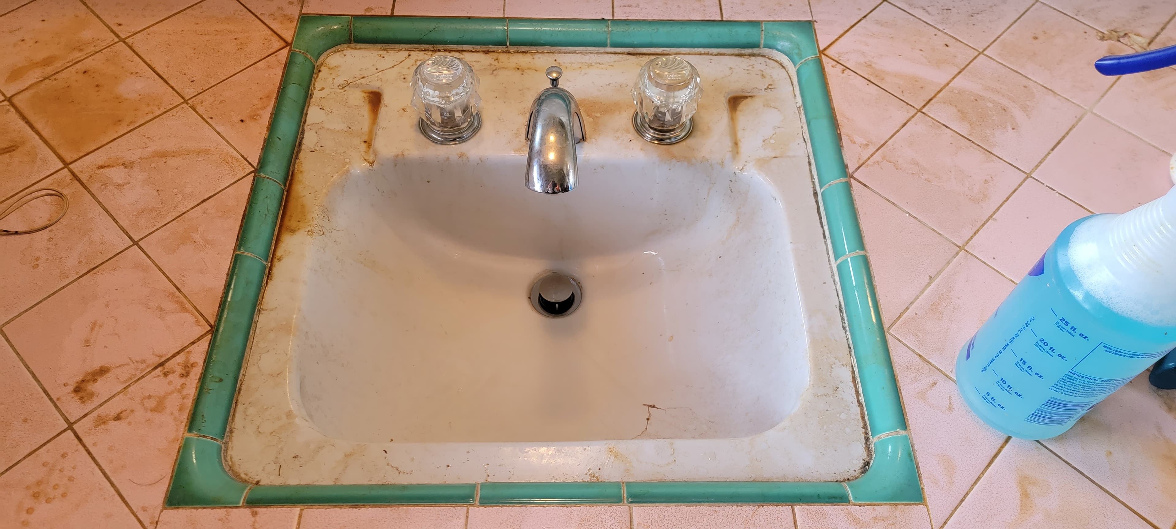 Pink tile sink before deep cleaning, with buildup around the basin and counter